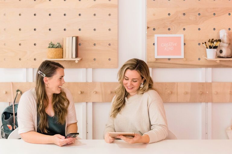 Two women sitting at a table, engrossed in a tablet. Two women sitting at a table, engrossed in a tablet.